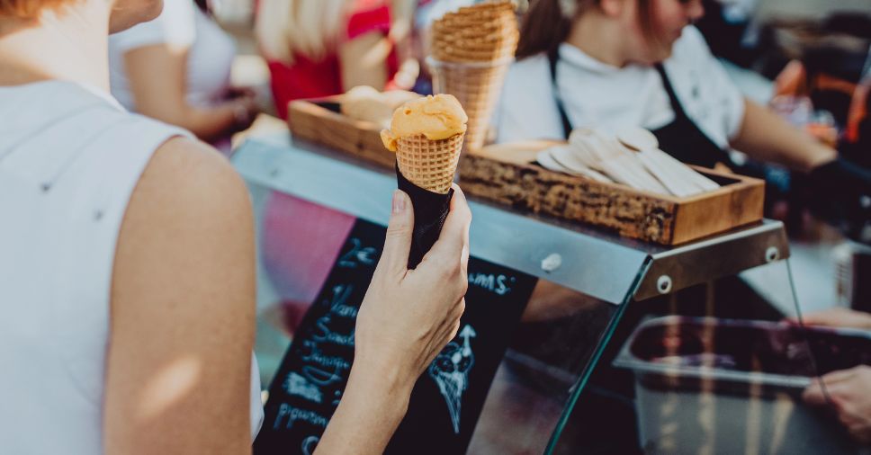 Cliente segura casquinha de sorvete em produção de sorvete artesanal.